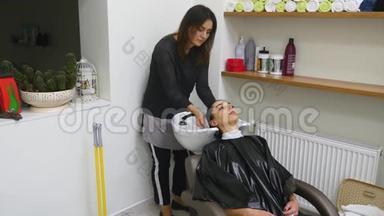 理发师在理发厅的一个现代盆里给客户洗头发，她正准备给客户理发